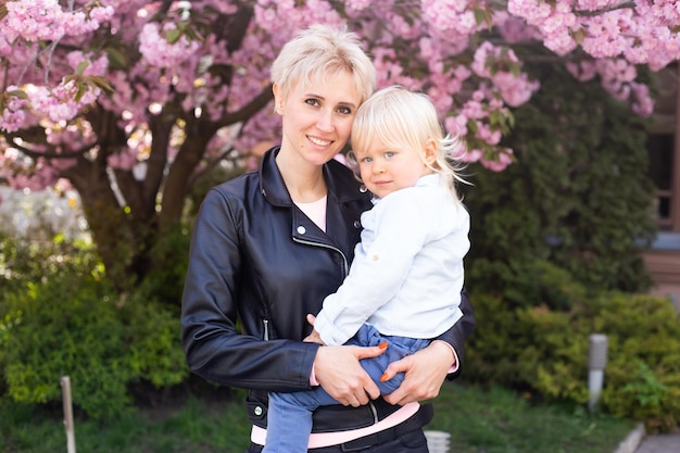 Mãe segurando seu filho bebê sob o conceito de primavera de cerejeiras Sakura florescendo