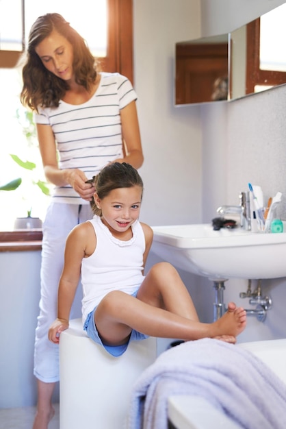 Mãe sempre dá penteados dignos de princesa Foto de uma mãe penteando o cabelo de suas filhas em casa