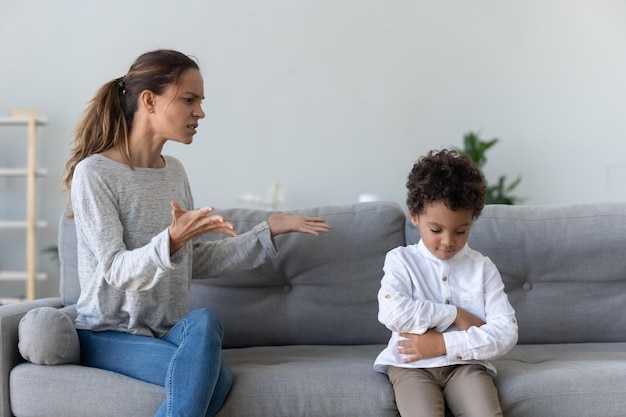 Mãe séria irritada repreendendo ensinando filho africano teimoso por mau comportamento em casa pai mãe mãe punir pequena raça mista criança culpada menino demanda disciplina conceito de conflitos familiares