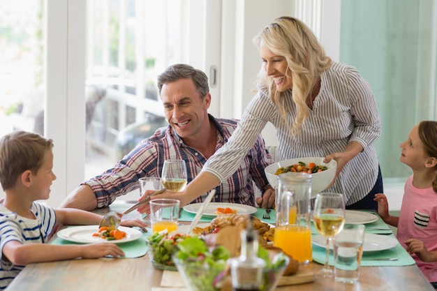 Mãe servindo comida para a família na mesa de jantar