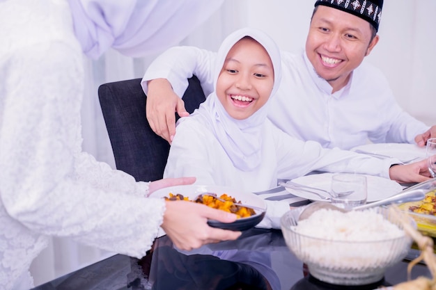 Mãe servindo comidas especiais para sua família no Eid
