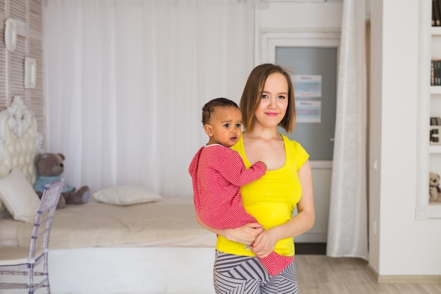 Mãe sorridente com filho bebê de raça mista em casa.