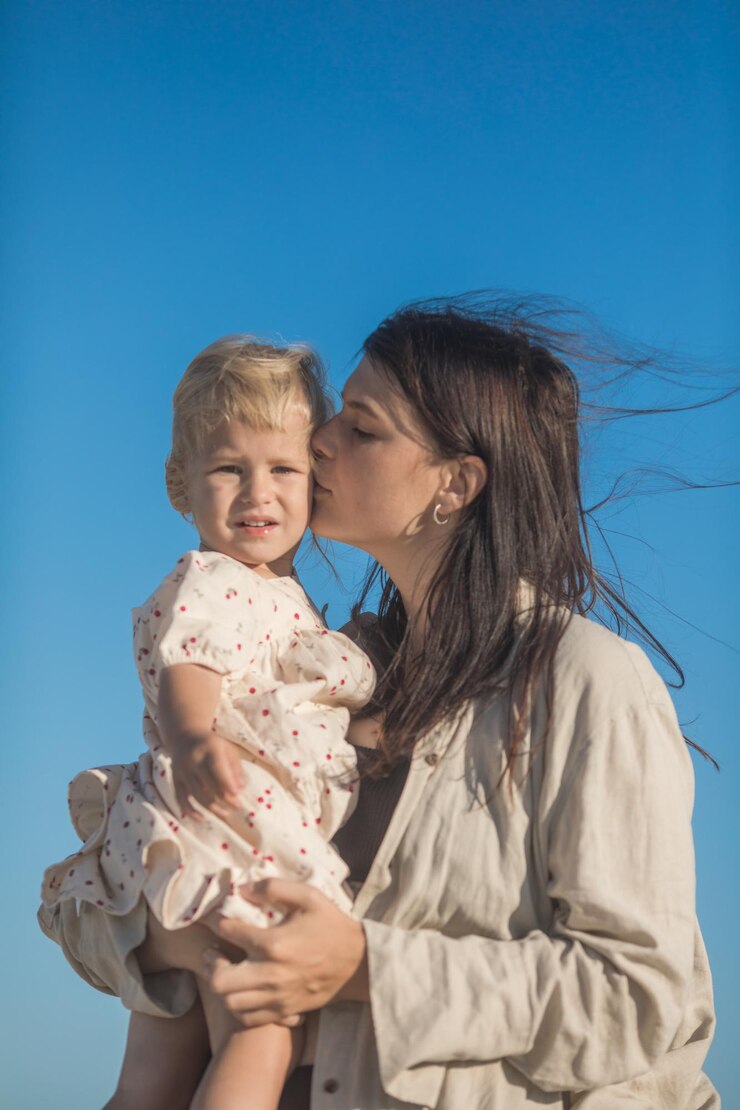 Mãe sorridente e bela filha se divertindo na praia Retrato de uma criança abraçando sua mãe durante o verão