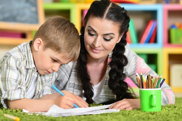 Mãe sorridente e filho a desenhar com lápis