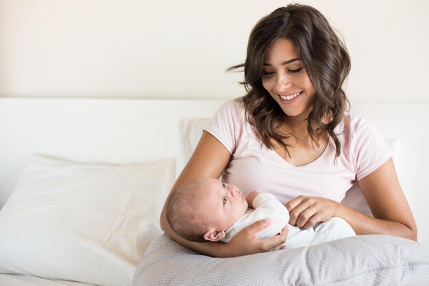 Foto mãe sorridente olhando para o filho enquanto está sentada no sofá em casa