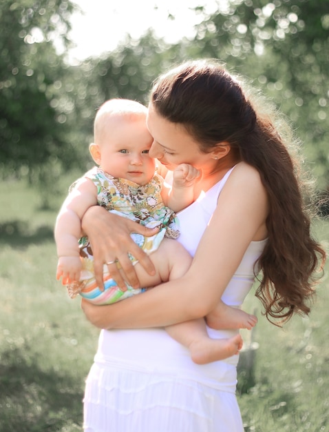 Mãe sorridente, segurando sua filha nos braços, conversando, olhando para o bebê com amor e adoração
