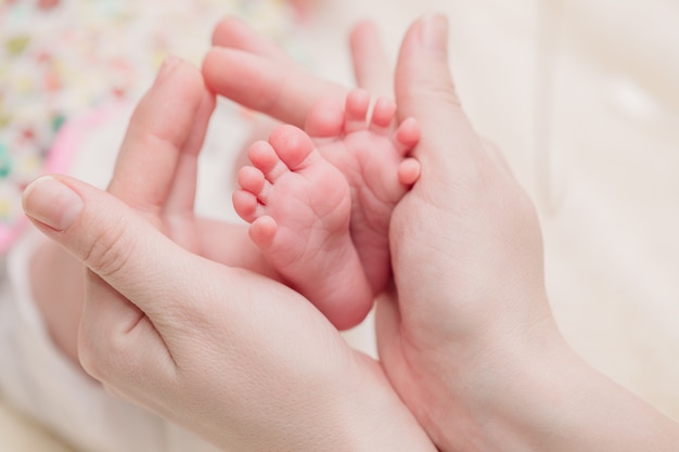 Mãe tem pequenas pernas de bebê nas mãos