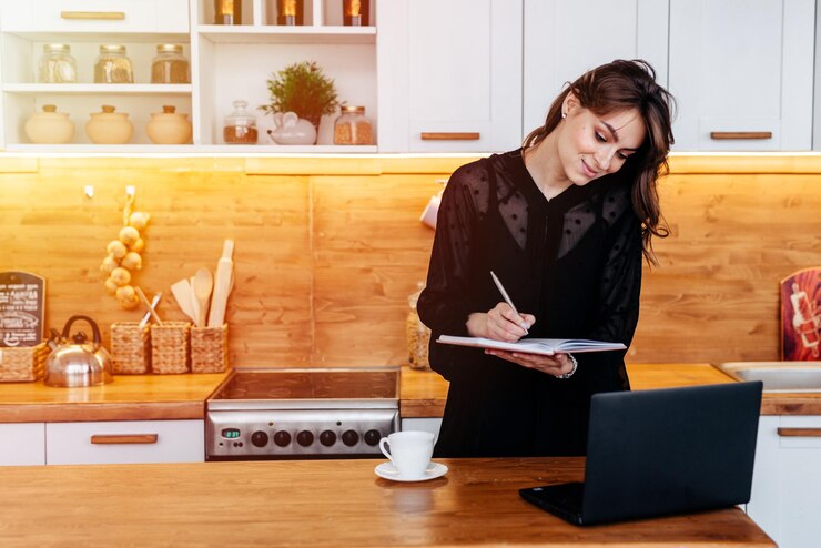 Foto mãe trabalhadora com escritório improvisado montado na cozinha usando vestido preto