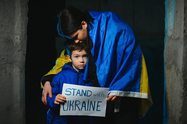 Foto mãe triste abraçando seu filho usando cores nacionais ucranianas em fundo preto