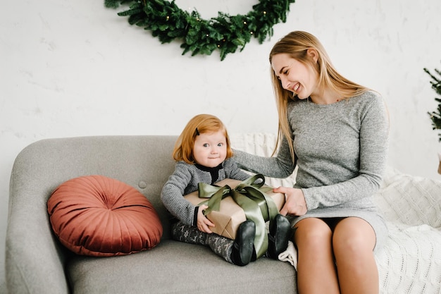 Mãe trocando presentes com a filha Pai e filho se divertindo perto da árvore de Natal dentro de casa Família amorosa com presentes no quarto Na manhã anterior ao Natal Retrato mãe e filho de perto