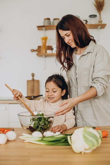 Mãe uma filha preparando salada cozinhando na cozinha