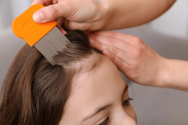 Mãe usando pente fino no cabelo da filha dentro de casa Tratamento anti-piolhos