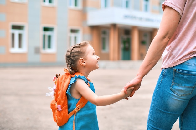 Mãe vai para a escola com a filha de mãos dadas