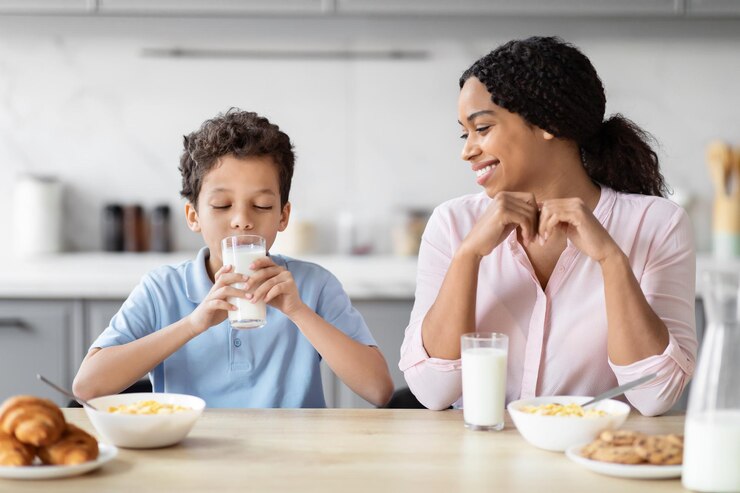 Foto mãe vendo filho beber leite no café da manhã