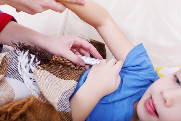 Mãe verificando a temperatura de seu bebê doente com um termômetro.