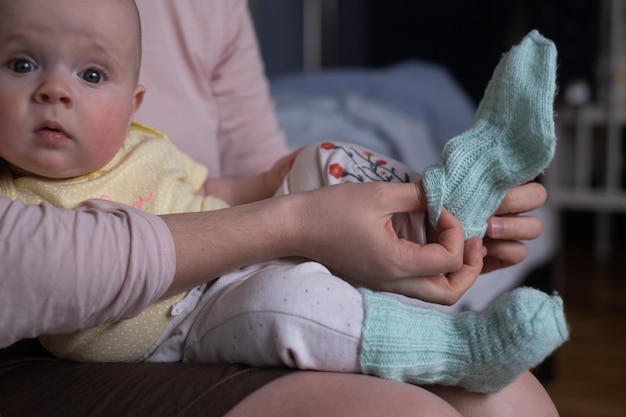 Mãe vestindo seu bebê usando meias porque está frio em casa