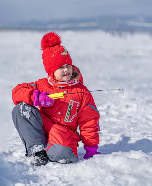 Mädchen 6 Jahre alt beim Winterangeln fängt Fische im Loch