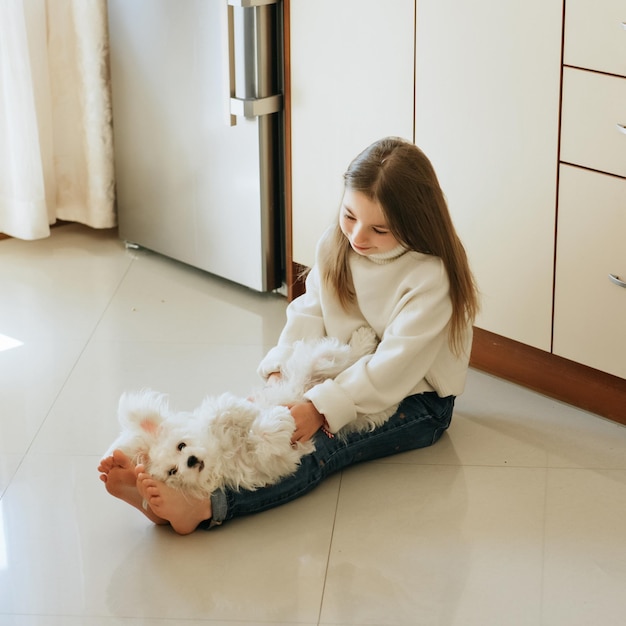 Foto mädchen 9 jahre alt mit langem haar modell mit einem hund maltesisches schulmädchen zu hause lifestyle