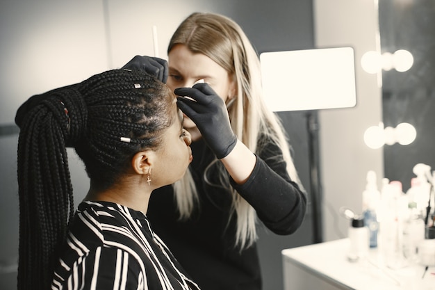 Mädchen Afrika. Frau, die Augenbrauen macht. Mädchen in einem Schönheitssalon.