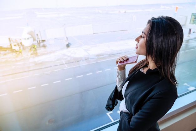 Mädchen am Flughafenfenster wartet auf einen Flug