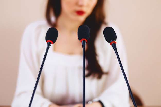 Mädchen am Tisch spricht in Mikrofone im Konferenzsaal