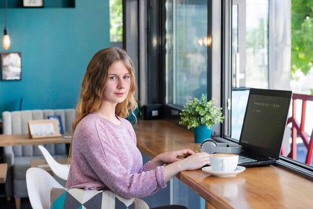 Mädchen arbeitet an einem Laptop für Fernarbeit in einem Café