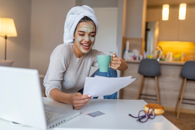 Mädchen arbeitet von zu Hause aus, sie hat eine Gesichtsmaske und sie ist im Bademantel.