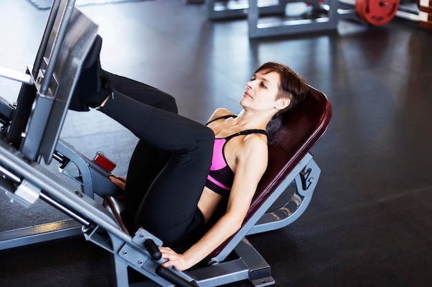 Mädchen auf dem Simulator im Fitnessstudio, das Übungen macht