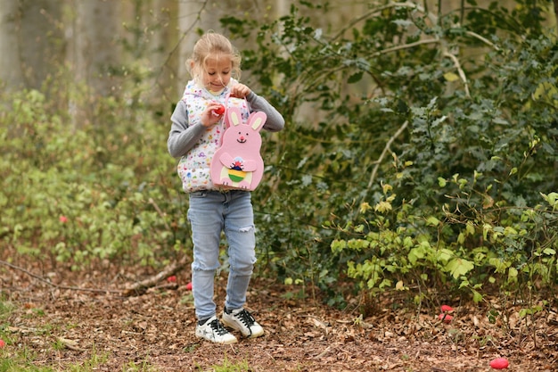 Mädchen auf der Suche nach Eiern in einer Tasche für Ostern