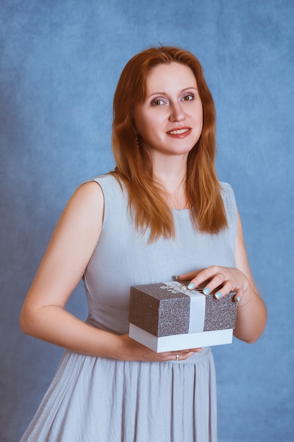 Mädchen auf einem blauen Hintergrund mit einem Geschenk