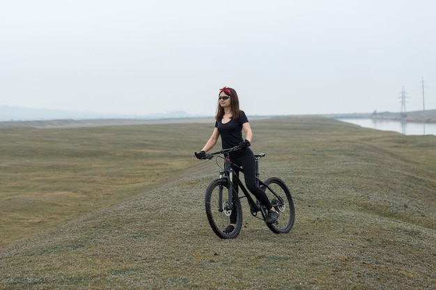 Mädchen auf einem Mountainbike im Gelände schönes Porträt eines Radfahrers bei Regenwetter Fitness-Mädchen reitet auf einem modernen Kohlefaser-Mountainbike in Sportbekleidung Nahaufnahmeporträt eines Mädchens in rotem Bandana