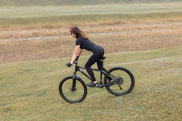 Mädchen auf einem Mountainbike im Gelände schönes Porträt eines Radfahrers bei Regenwetter Fitness-Mädchen reitet auf einem modernen Kohlefaser-Mountainbike in Sportbekleidung Nahaufnahmeporträt eines Mädchens in rotem Bandana
