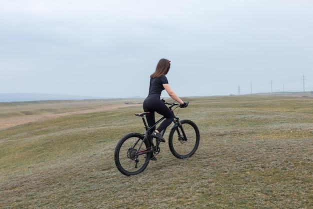 Mädchen auf einem Mountainbike im Gelände schönes Porträt eines Radfahrers bei Regenwetter Fitness-Mädchen reitet auf einem modernen Kohlefaser-Mountainbike in Sportbekleidung Nahaufnahmeporträt eines Mädchens in rotem Bandana