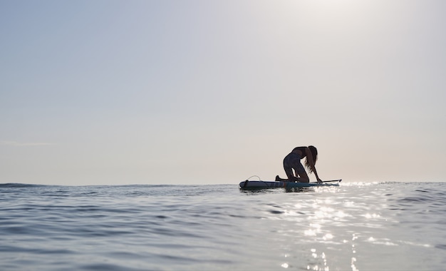 Mädchen auf einem Paddle Board bei Sonnenaufgang