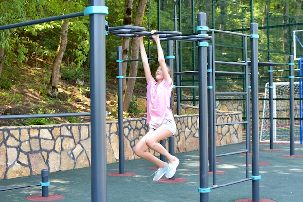 Mädchen auf Outdoor-Sportplatz. Teenager-Mädchen, das Gymnastikübungen im Fitnessstudio im Freien macht.