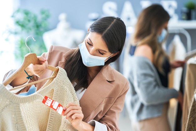 Mädchen beim Einkaufen im Geschäft mit Kleidung, die Masken trägt. Foto in hoher Qualität