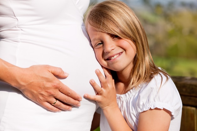 Mädchen berühren Bauch der schwangeren Mutter