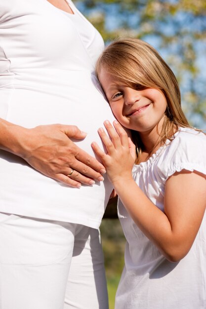 Mädchen berühren Bauch der schwangeren Mutter