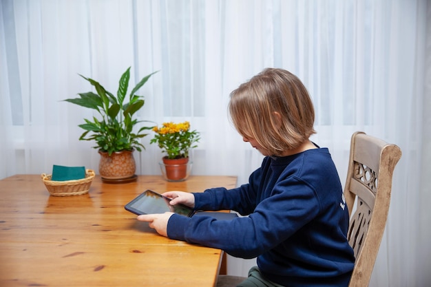 Mädchen beschäftigt sich auf Tablet fern von zu Hause am Tisch