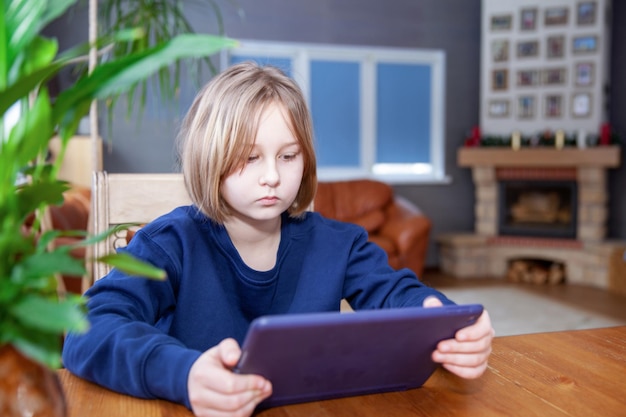 Mädchen beschäftigt sich auf Tablet fern von zu Hause am Tisch