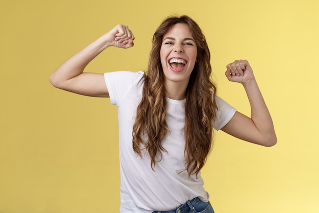 Mädchen danke Einladung tolle Party, die Spaß hat, wild zu werden, die Hände hochheben, entspannt, locker tanzen, Lippensynchronisation coole Musik, den Moment genießen, ein weißes T-Shirt tragen, ein lässiges Outfit, das gelben Hintergrund feiert