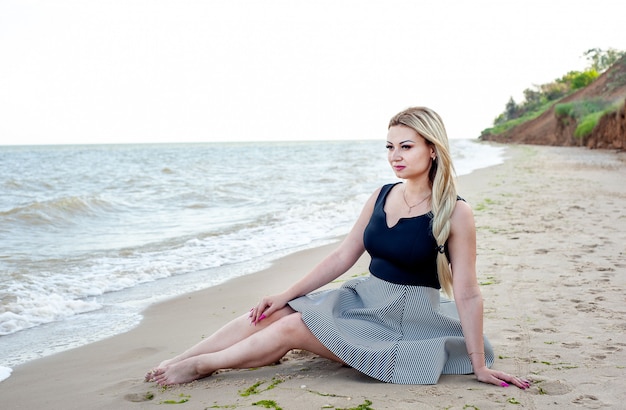 Mädchen, das am Strand bei bewölktem Wetter in einem Kleid geht