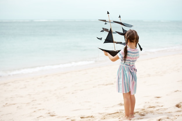 Mädchen, das am Strand mit Schiffsdrachen spielt