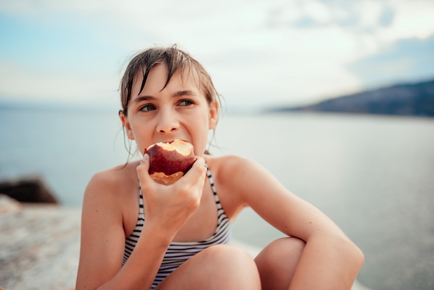 Mädchen, das Apfel am Strand isst