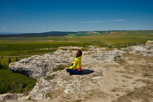 Mädchen, das auf dem Gipfel des Berges meditiert und Yoga macht