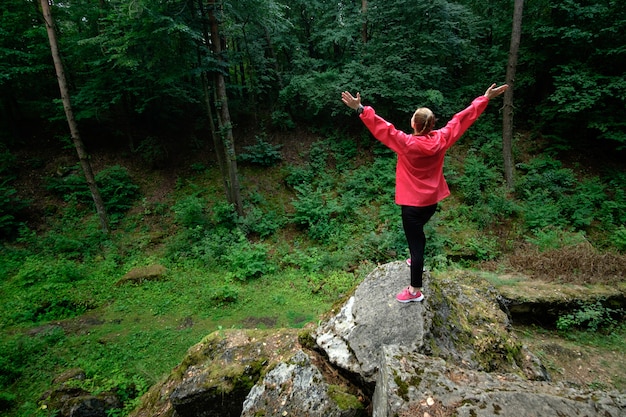 Mädchen, das auf einem Felsen in einem Wald steht. Travel.g