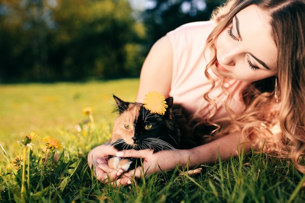 Mädchen, das auf Gras mit Katze liegt. Konzept für warmes Wetter im Frühling oder Sommer.