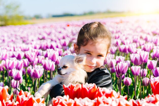 Mädchen, das auf Tulpenfeldern in der Region Amsterdam, Niederlande sitzt. Magische niederländische Landschaft mit Tulpenfeld