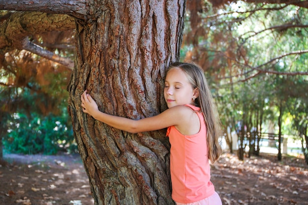 Mädchen, das Baum im Park umarmt.