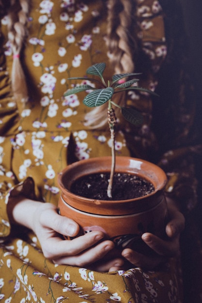 Mädchen, das Blumen in einem Topf hält